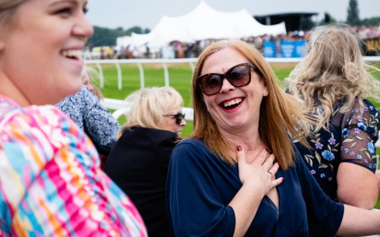 A racegoer at Worcester Racecourse laughs with friends